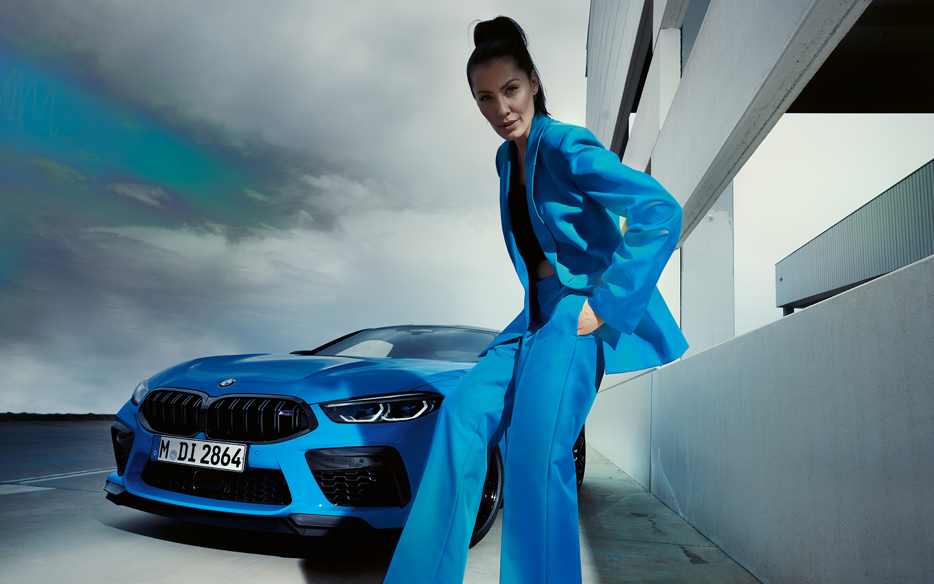 BMW M8 Competition Coupé F92 LCI 2022 Dreiviertel-Frontansicht BMW M8 Competition Coupé F92 LCI Facelift 2022 Daytona Beach Blau Uni Dreiviertel-Frontansicht mit weiblichem Model in blauem Hosenanzug