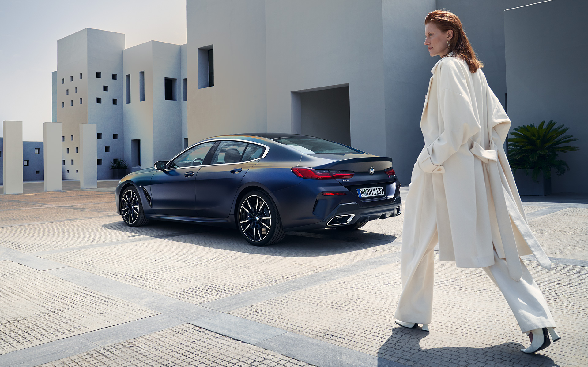BMW M850i xDrive Gran Coupé G16 LCI restylage 2022 vue de profil avec modèle féminin BMW M850i xDrive Gran Coupé G16 LCI restylage 2022 BMW Individual Frozen Tansanitblau metallic vue de trois quarts arrière avec modèle féminin