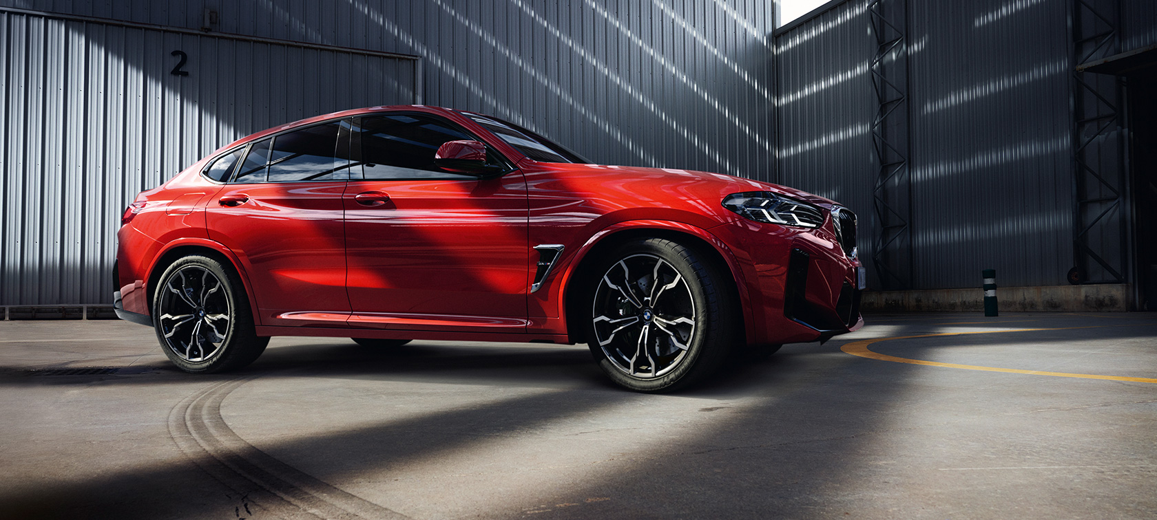 Vue de trois quarts face BMW X4 M F98 LCI Facelift 2021 BMW X4 M F98 LCI Facelift 2021 Toronto Rot metallic vue de trois quarts face dans un bâtiment d'usine