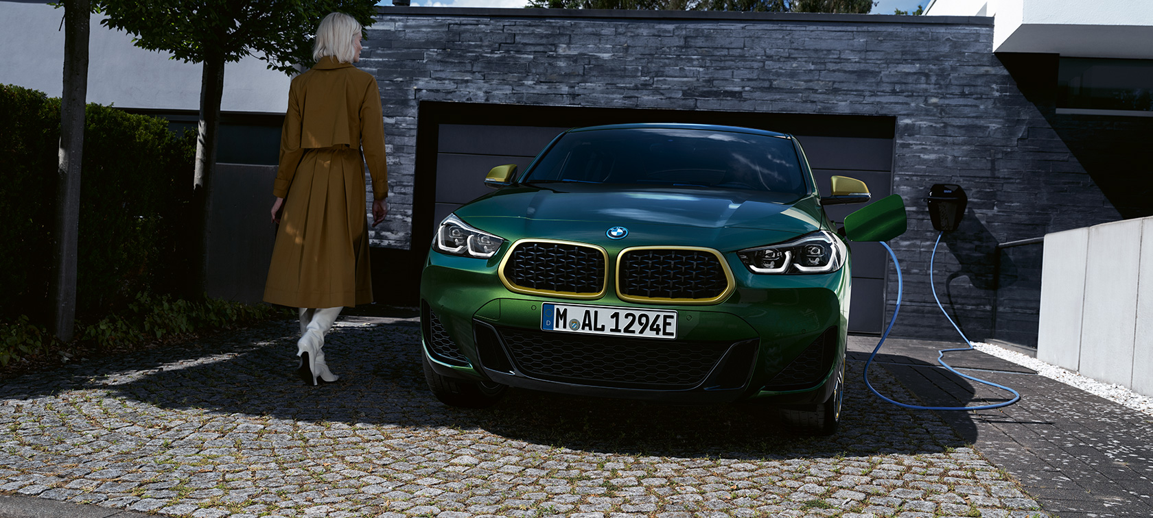 Frontansicht BMW X2 F39 Sanremo Green metallic Frontansicht in Ladesituation mit Model links BMW X2 F39 Sanremo Green metallic