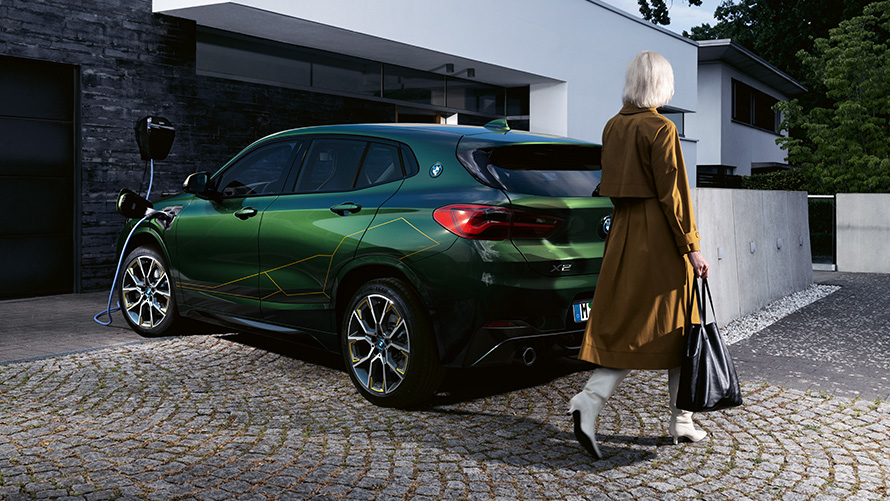 BMW X2 F39 Sanremo Green metallic Dreiviertel-Heckansicht mit Model BMW X2 F39 Sanremo Green metallic Dreiviertel-Heckansicht mit Model