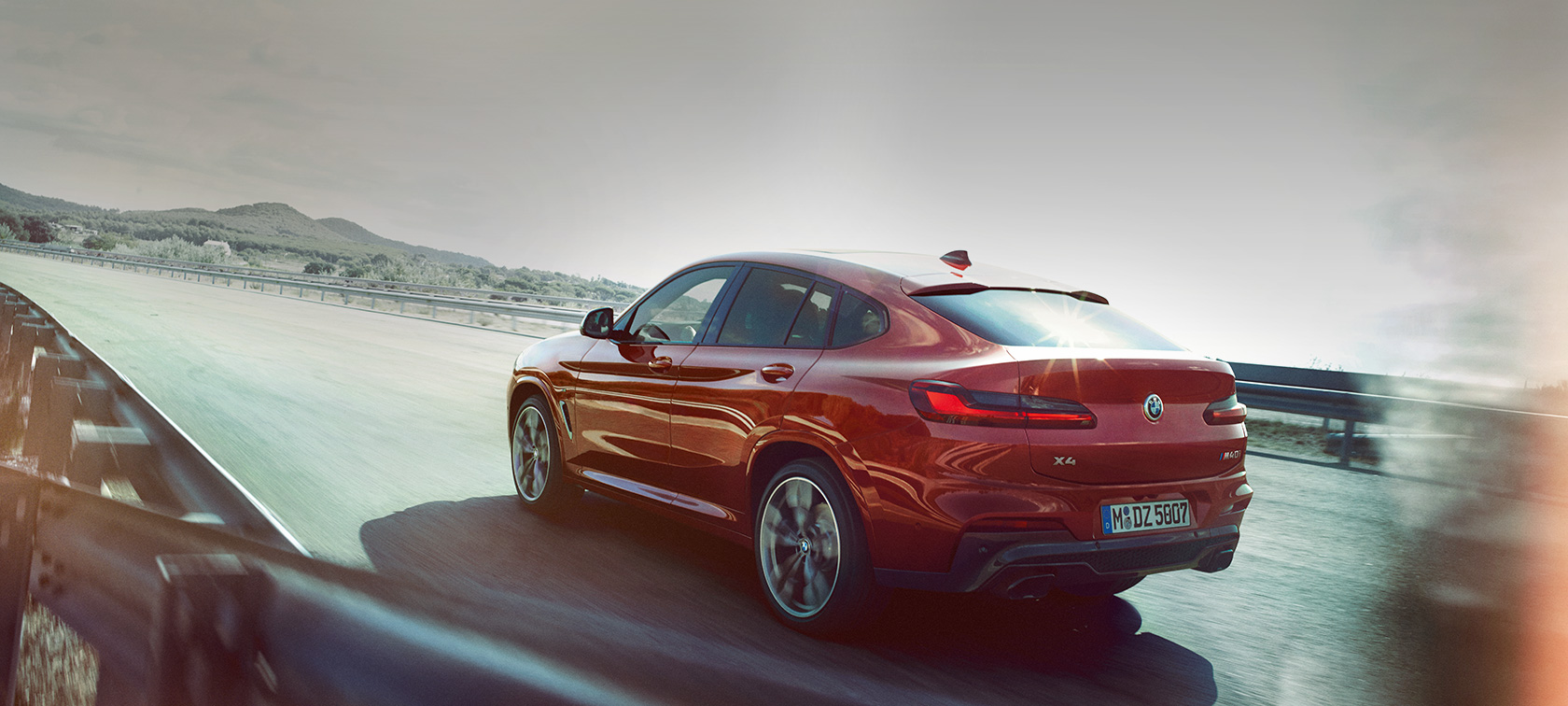 BMW X4 SUV fahrend auf der Straße G02 BMW X4 M40i SUV G02 2018 Flamencorot Brillanteffekt Rot Dreiviertel-Heckansicht fahrend auf der Straße