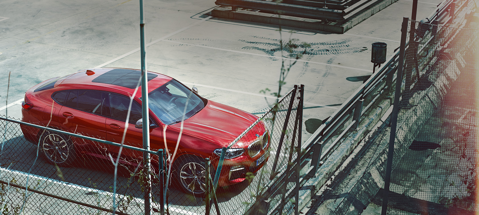 BMW X4 en stationnement G02 BMW X4 G02 2018 en Flamencorot Brillanteffekt en stationnement sur un parking couvert, vue en plongée