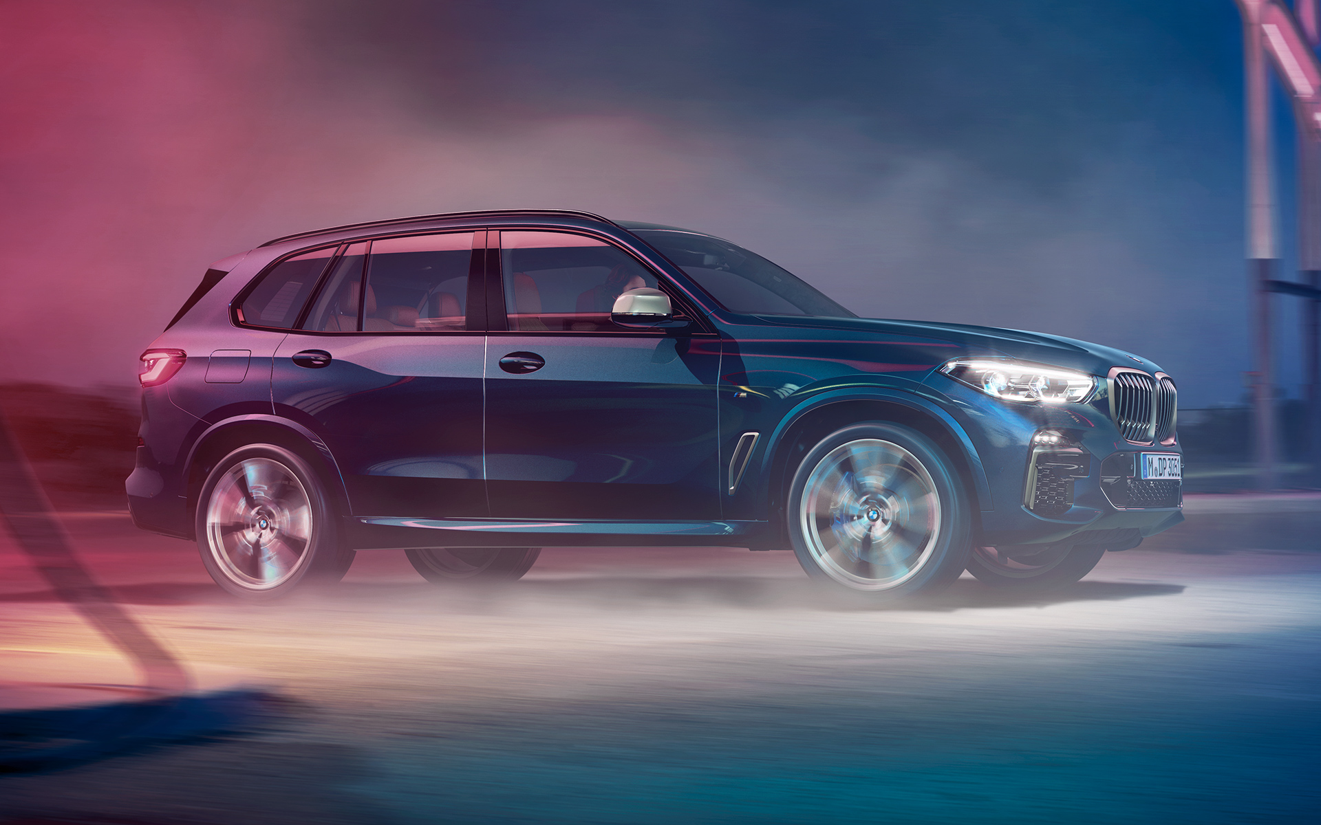 BMW X5 M50d fahrend Fahraufnahme des BMW X5 M50d in der Nacht vor Stadtkulisse