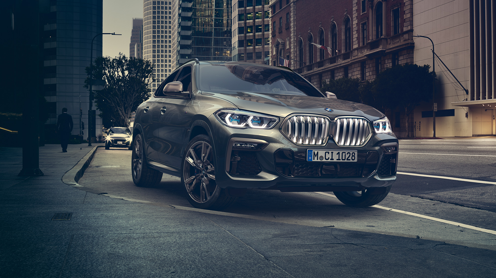 BMW X6 adaptives M Fahrwerk Professional. G06 BMW X6 in Dreiviertel-Front Perspektive vor urbaner Kulisse. G06