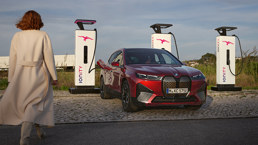 BMW Special Sales Sustainability Hub Overview BMW Charging Solutions BMW Fahrzeug an Ladestation mit Frau im Vordergrund