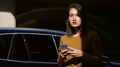 BMW ConnectedDrive Aperçu femme avec smartphone devant BMW