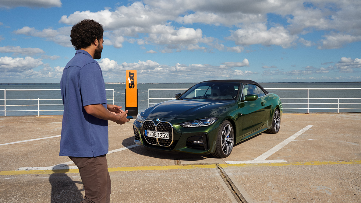 Application BMW Add-On Mobility vidéo Application BMW Add-On Mobility vidéo homme avec un smartphone dans les mains devant la BMW Série 4 Cabrio et inscription SIXT en arrière-plan