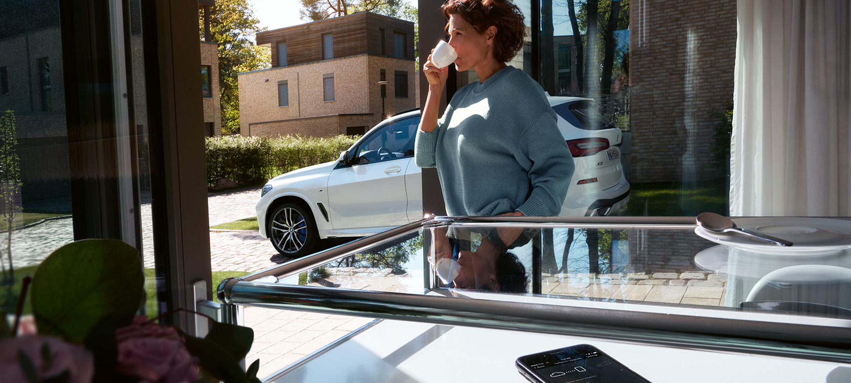 BMW Remote Software Upgrade Une femme boit dans une tasse tandis que BMW Remote Software Upgrade met à jour le logiciel embarqué de sa BMW X5
