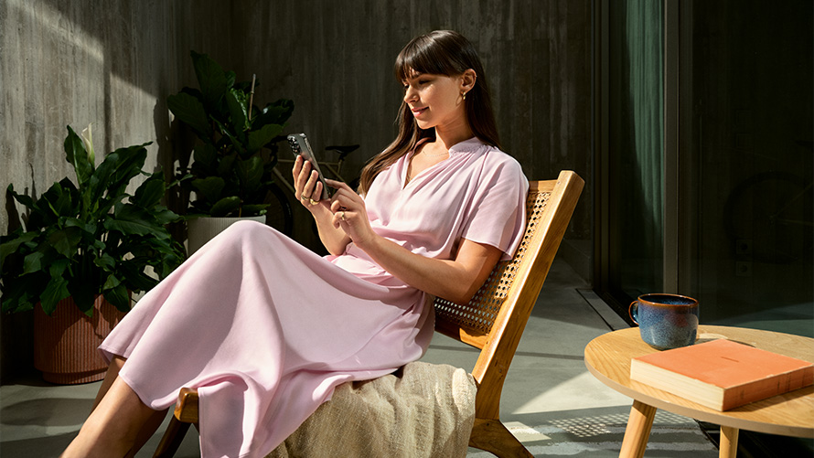 Femme en robe rose avec un smartphone à la main Remote Inside View Remote Inside View femme en robe rose sur une chaise avec un smartphone à la main
