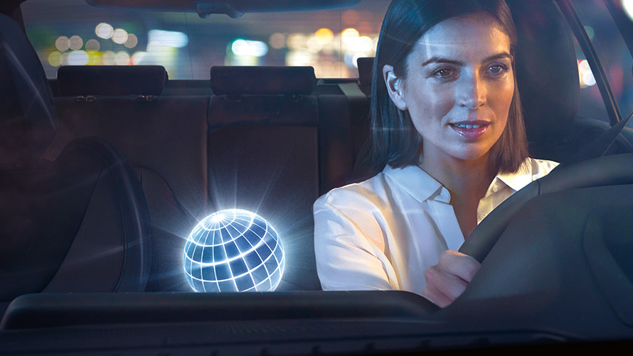 BMW Intelligent Personal Assistant Frau fährt in BMW bei nächtlicher Kulisse
