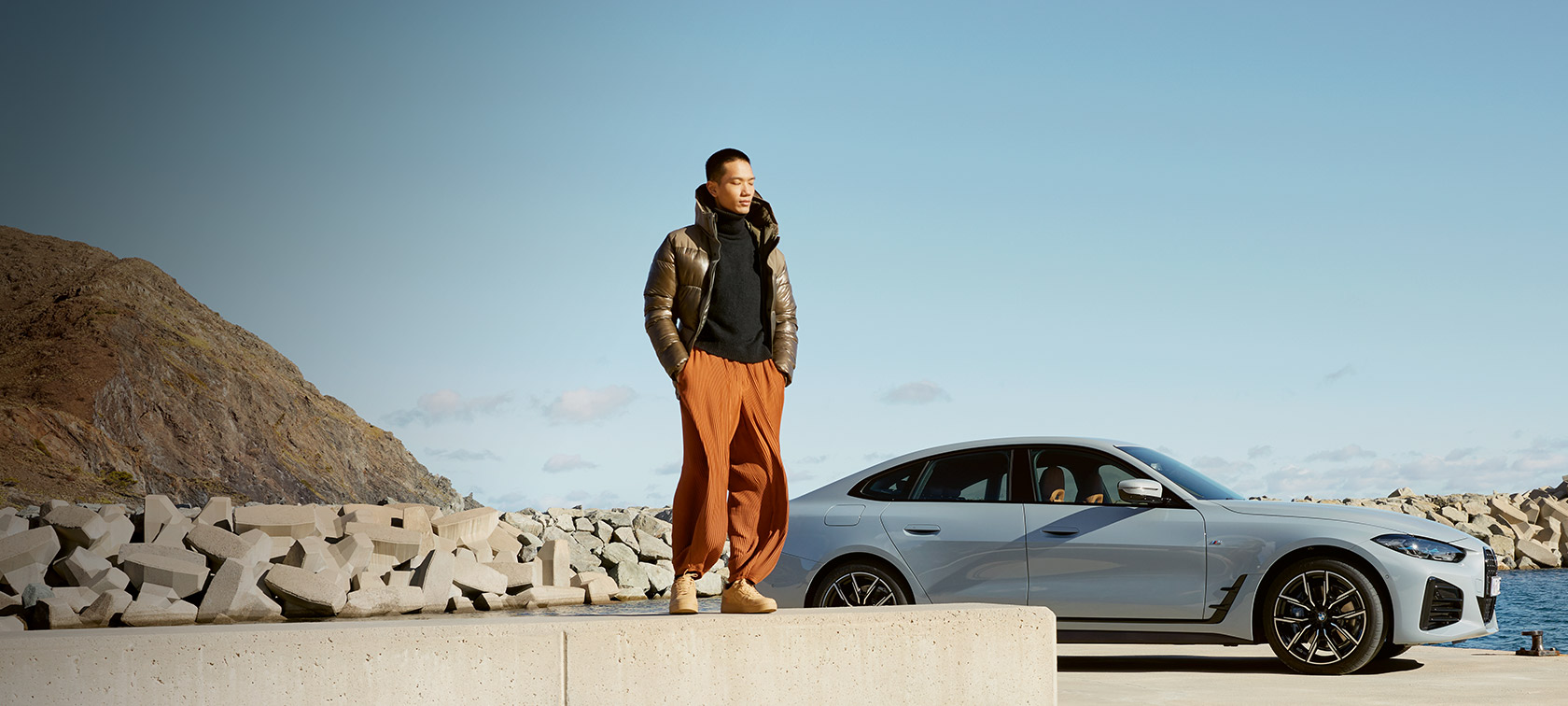 BMW Service Inclusive BMW Service Inclusive Mann vor BMW i4 an der Küste