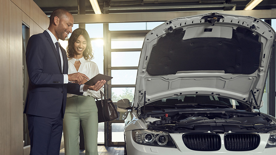 Check und Wartung BMW Service Kundin und BMW Service Mitarbeiter besprechen Check und Wartung am BMW