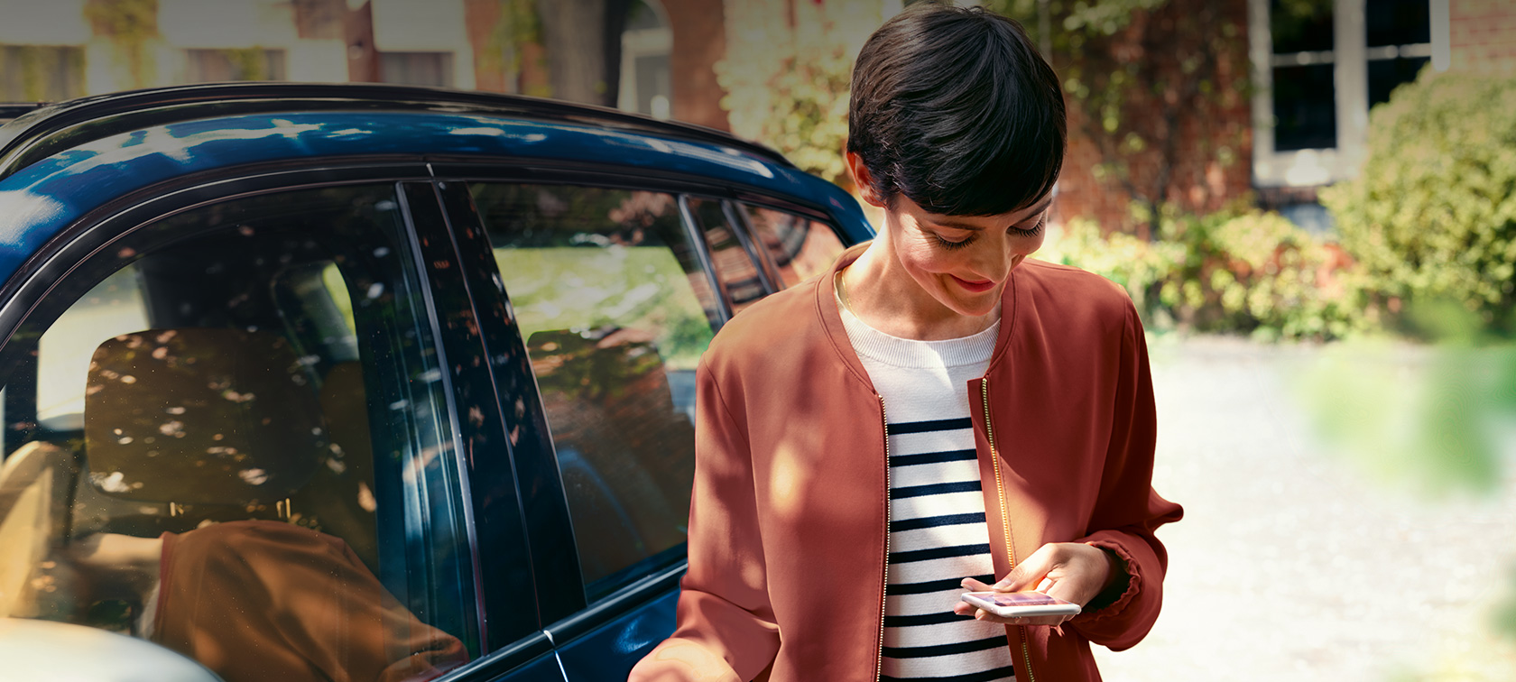 BMW Teleservices Frau guckt auf ihr Smartphone BMW Teleservices Frau vor BMW guckt auf ihr Smartphone