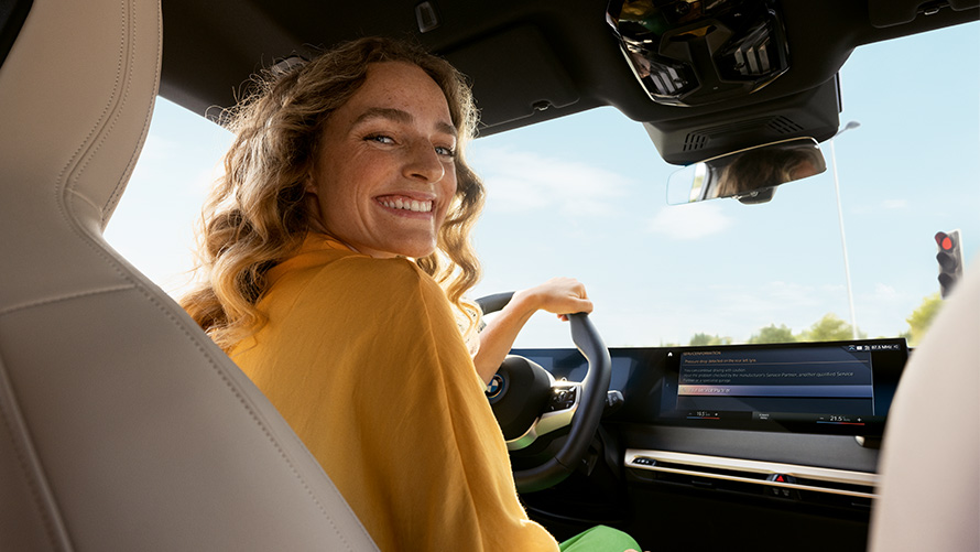 Fonctionnement Proactive Care Proactive Care, contrôle & entretien Fonctionnement Proactive Care Proactive Care, contrôle et entretien, femme assise une main sur le volant à bord du véhicule BMW
