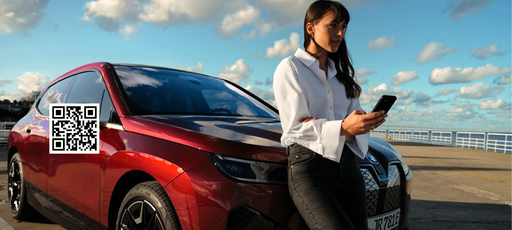 Frau vor BWW iX und benutzt My BMW App auf Smartphone Frau vor BWW iX und benutzt My BMW App auf Smartphone