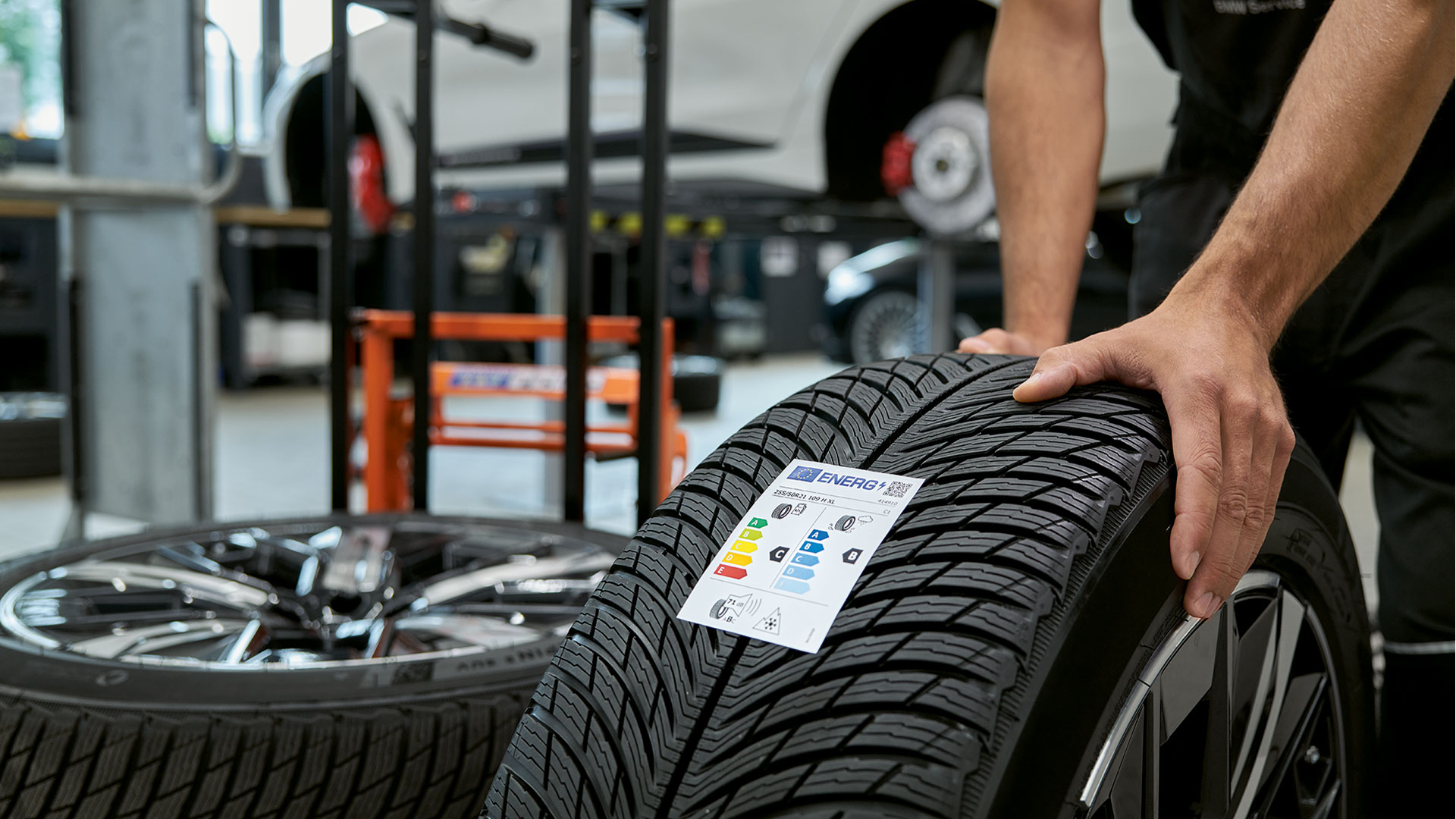 BMW reparaties en verzorging My BMW App vrouw met smartphone in de handen leunt tegen BMW wagen.